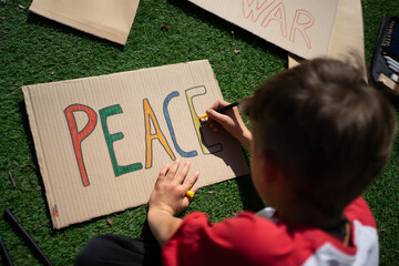 Child drawing peace sign on cardboard promoting harmony and love