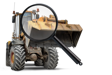 A magnifying glass highlights a heavy machinery loader, showcasing its rugged details and inviting careful inspection for rental assessments and analyses.
