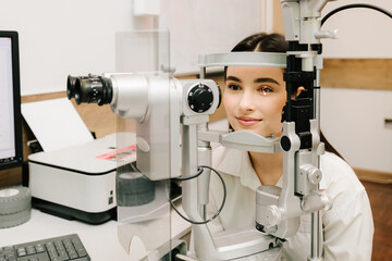 Ophthalmologist illuminates eye of patient with light from slit lamp to diagnose the eyes and...