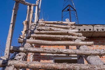 Old dilapidated building with homemade wooden staircase in rural area