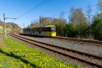 Obraz premium Spring landscape with a yellow tram traveling towards a destination in Manchester UK 