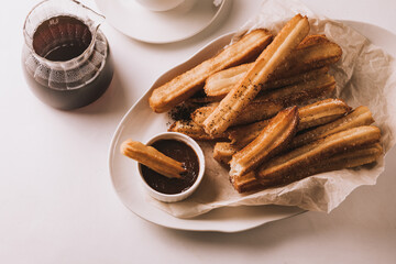 Traditional spanish treat street fast food churros on a plate with hot chocolate sauce.