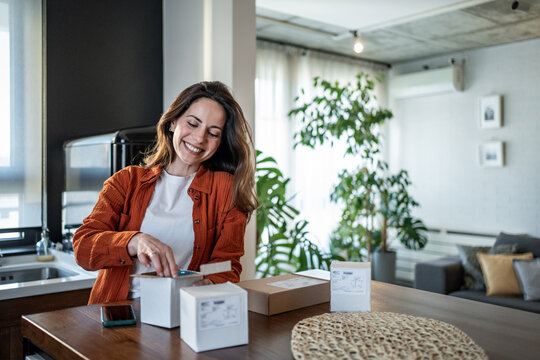 Happy woman opening package at home in kitchen