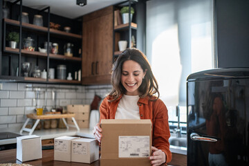 Woman opening package at home in kitchen, receiving online order