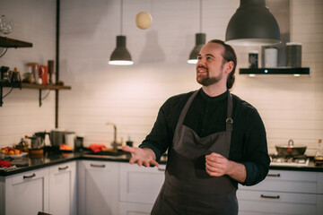 A male chef prepares noodles at home in the kitchen.