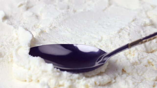 Fresh white ricotta cheese spreading with spoon close up