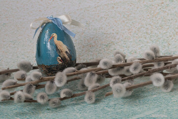 A bouquet of catkins and a decorative Easter egg with a stork motif 