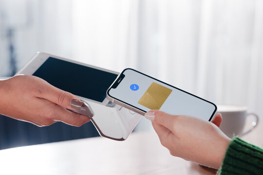 Closeup of smartphone contactless payment using NFC on terminal at cozy cafe. - Powered by Adobe