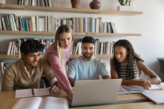 Problem solving and academic teamwork. Young gen z girl take lead with diverse team of multiethnic teenage students explain project on notebook screen to classmates group mentoring friends in learning
