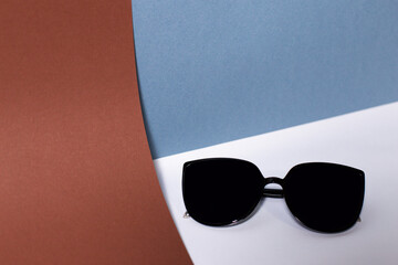 Sunglasses, black glasses on blue, white and brown background