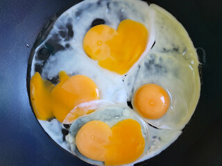 An egg yolk in the shape of a heart is fried in a frying pan