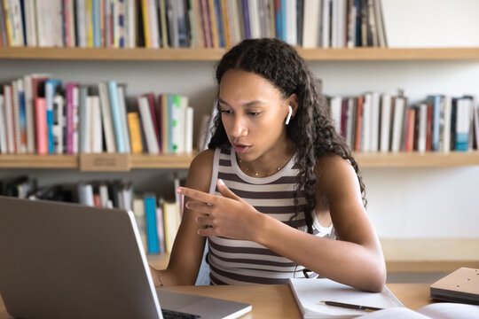 Online study session. Confident gen z female remote student wearing portable headphones looking at notebook screen speaking at virtual class workshop presenting idea on webinar answer teacher question