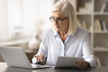 Financial review. Busy senior woman accountant lawyer engaged in paperwork at office workplace...