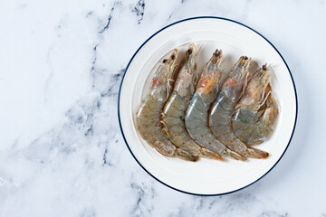 Fresh raw white-footed shrimp, tiger prawns vannamei, on a white plate,