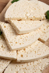 sliced Georgian cheese, factory grade, on a wooden board, top view,