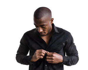 A man with dark skin and a closely shaved head buttons his black shirt, focusing downwards in a moment of preparation and looking formal.