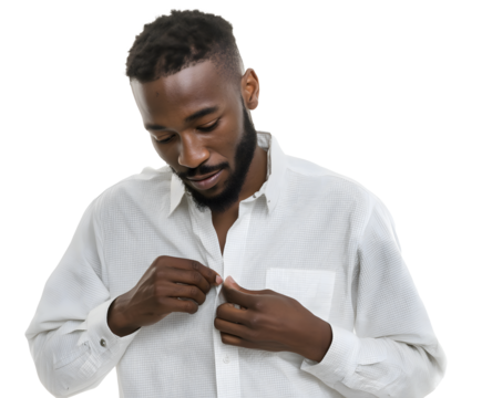 A bearded man in a white textured button-down shirt carefully fastens the buttons, looking down with a focused expression against a dark backdrop.