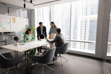 Successful company meeting room space with team of four colleagues, stakeholders, partners sitting...