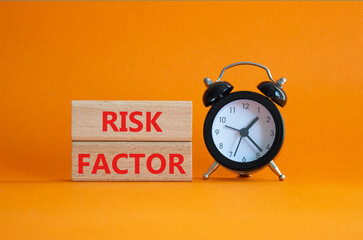 Risk Factor symbol. Wooden blocks with words Risk Factor Beautiful orange background with alarm clock. Business and Risk Factor concept. Copy space.
