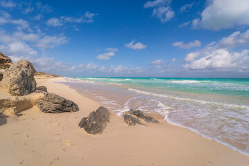 Playa tropical con rocas y mar turquesa bajo cielo azul despejado