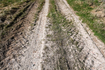 Tire tracks crossing a field on a dirt road creating a path