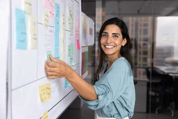Happy beautiful Hispanic businesswoman working on project management strategy, planning business...
