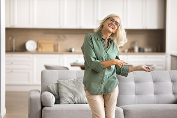 Active and happy retirement. Energetic joyful mature female pensioner dancing jumping with...