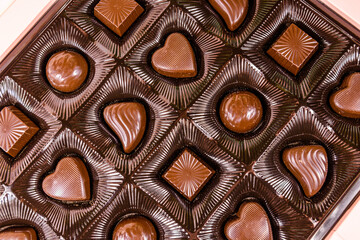Heap of chocolate candies in a brown box. Top view