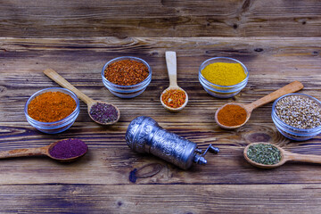 Spoons and bowls with oriental spices and spice mill on a wooden table