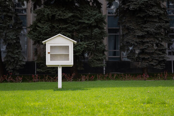 Small white house box with one shelf on a green grass