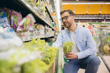 Customer buying groceries in supermarket, choosing fresh lettuce