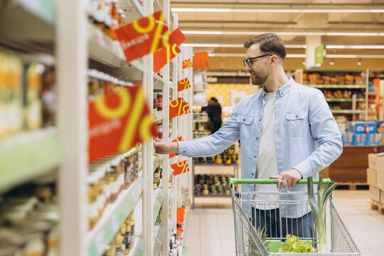 Customer choosing groceries in supermarket with discount offers