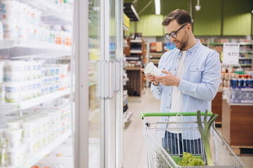 Customer choosing yogurt in refrigerated section at supermarket