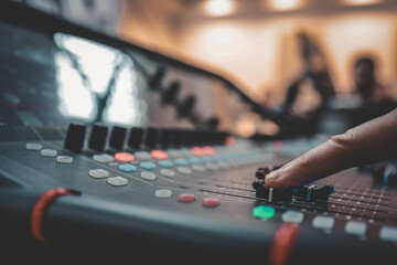 Close-up of a person adjusting sound levels on an audio mixing console during a live event or...