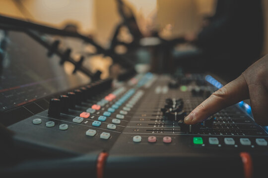 Close-up of a person adjusting sound levels on an audio mixing console during a live event or performance