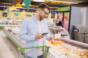 Customer Using Smartphone Choosing Cheese in Supermarket