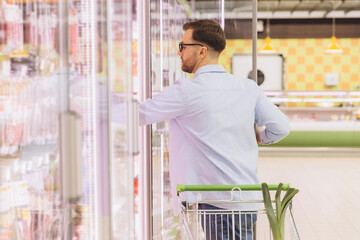 Man choosing frozen food from refrigerated section in supermarket