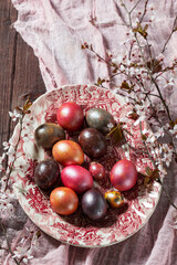 Eggs painted in different colors and covered with mother-of-pearl, and blossoming plum branches. Easter concept.