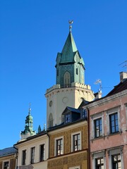 Naklejka premium Historical centre of Lublin, Poland. Tower with a green, pointed roof and decorative elements rises above historical buildings. Fishman’s orange building has intricate designs