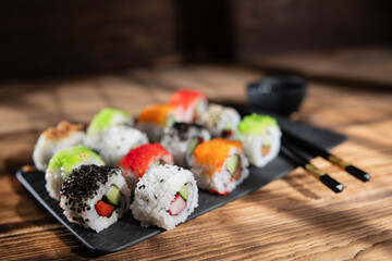 Colorful sushi rolls served on a black slate plate in a cozy restaurant setting during lunchtime