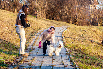 Fototapeta premium One spring day with a very beautiful sun, two girls were surprised while they were walking with a very beautiful white dog. The girls were the happiest to have such an animal friend.