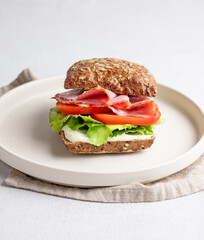 Toast sandwich made of grain bread with prosciutto, cheese, tomatoes, lettuce and sauce on a plate
