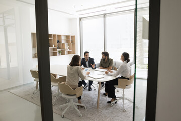 Multinational businessmen and businesswomen take part in brainstorming event, strategy planning, or problem-solving discussion, develop new ideas, review charts, do paperwork together during meeting