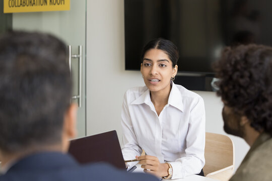 Meeting of businesspeople in office, focus on young 25s Indian woman listening attentively, passing job interview in office, talk to HR managers, answers questions. Human resources, negotiations event