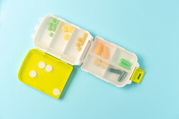 Pill box organizer on blue background. Flat lay, top view. Copy space