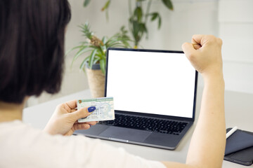 Woman holding permanent resident (green) card on hand and doing winner gesture celebrate clenching...