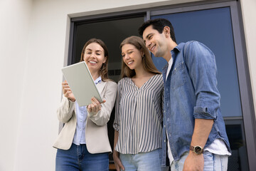 Real estate consultation, and modern home buying experience. Female realtor showing to young couple...