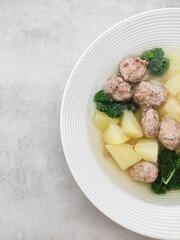 Wedding soup with meatballs, potatoes and parsley in white bowl copy space