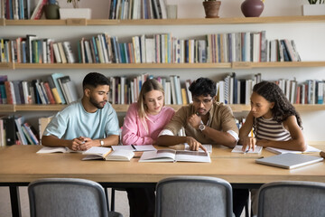 Collaboration in learning. Busy multiethnic young people college university students team study scientific literature at campus library prepare for test exam work together on group research with books