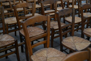 Rows of wooden chairs in an old church or hall. Vintage seating arrangement with warm wood tones and classic atmosphere, symbol of tradition, community, and history.